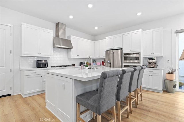 27120 Purple Sage Ct, Valencia, CA 91381 - kitchen with wall chimney range hood, appliances with stainless steel finishes, a kitchen breakfast bar, white cabinets, and recessed lighting
