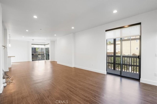 unfurnished living room with wood finished floors, baseboards, and recessed lighting