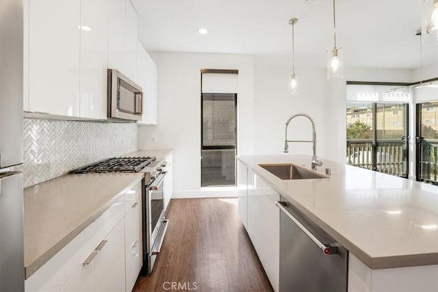 kitchen with appliances with stainless steel finishes, a sink, dark wood finished floors, backsplash, and modern cabinets