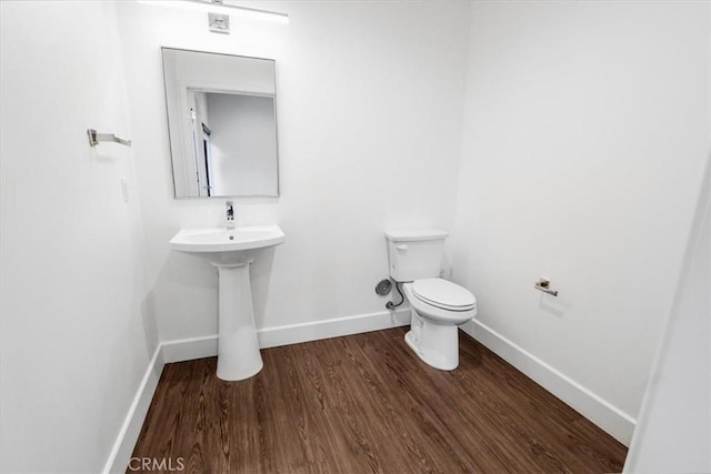 half bathroom featuring baseboards, toilet, and wood finished floors