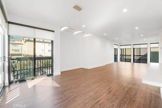 spare room featuring wood finished floors, plenty of natural light, recessed lighting, and baseboards