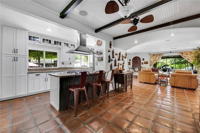 22658 Arriba Dr, Saugus, CA 91350 - kitchen featuring range hood, beam ceiling, a breakfast bar area, white cabinetry, and plenty of natural light
