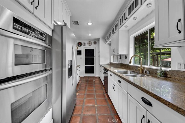 22658 Arriba Dr, Saugus, CA 91350 - kitchen with a sink, appliances with stainless steel finishes, white cabinetry, glass insert cabinets, and dark stone counters