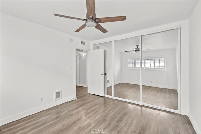 unfurnished bedroom featuring wood finished floors, baseboards, a closet, and a ceiling fan