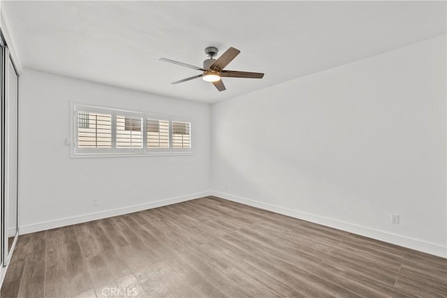 empty room featuring ceiling fan, wood finished floors, and baseboards
