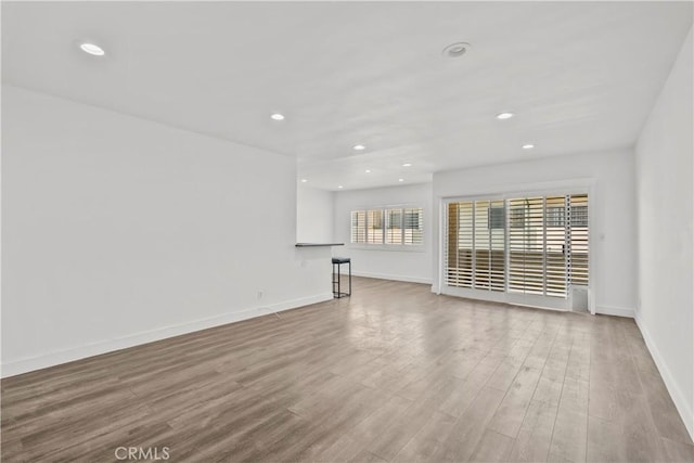 unfurnished living room with wood finished floors, recessed lighting, and baseboards