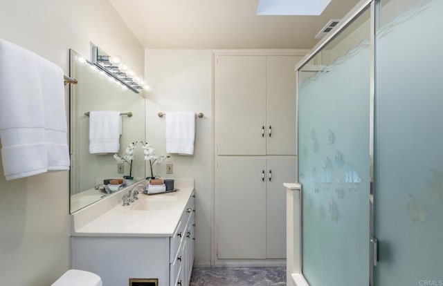 bathroom with a shower stall, vanity, a skylight, and toilet