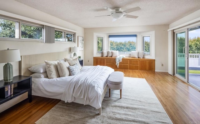bedroom with access to outside, a textured ceiling, wood finished floors, and ceiling fan