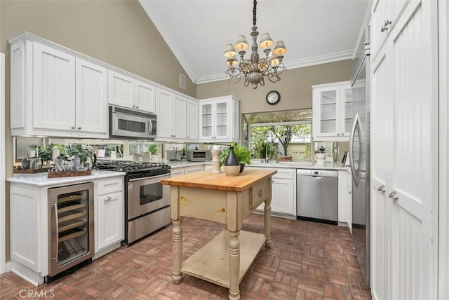 19 Rollins Pl, Laguna Niguel, CA 92677 - kitchen with stainless steel appliances, wine cooler, white cabinetry, crown molding, and high vaulted ceiling