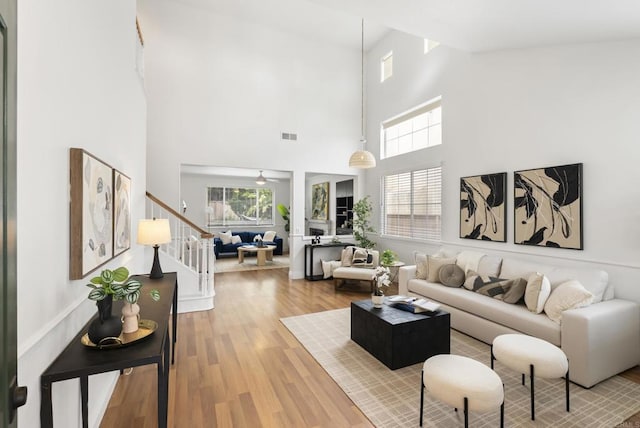 living room featuring stairway, healthy amount of natural light, wood finished floors, and a high ceiling