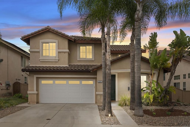 view of front of home with a tiled roof, stucco siding, a garage, and concrete driveway