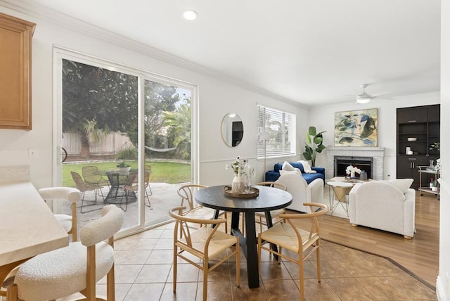 dining area featuring crown molding, a ceiling fan, a fireplace, light wood-style floors, and recessed lighting
