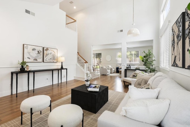 living area with stairway, wood finished floors, a high ceiling, and recessed lighting