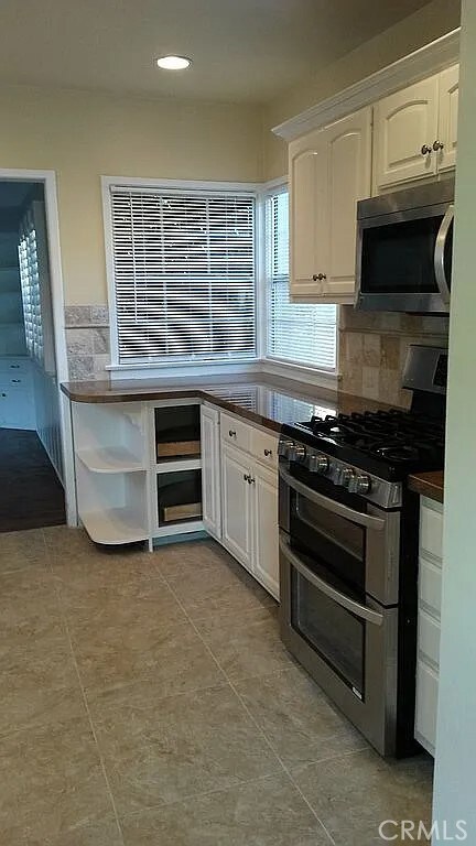 527 S Orchard Dr, Burbank, CA 91506 - kitchen with appliances with stainless steel finishes, open shelves, white cabinets, dark countertops, and light tile patterned flooring