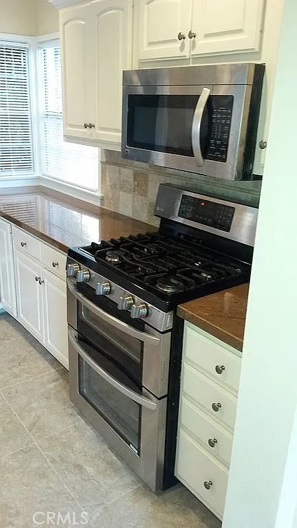 527 S Orchard Dr, Burbank, CA 91506 - kitchen with appliances with stainless steel finishes, white cabinets, decorative backsplash, dark countertops, and light tile patterned floors