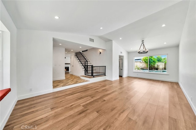 25735 Williamsburg Ct, Lake Forest, CA 92630 - unfurnished living room featuring a warm lit fireplace, light wood finished floors, lofted ceiling, a chandelier, and baseboards