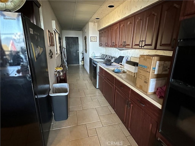 kitchen with light countertops, freestanding refrigerator, and independent washer and dryer