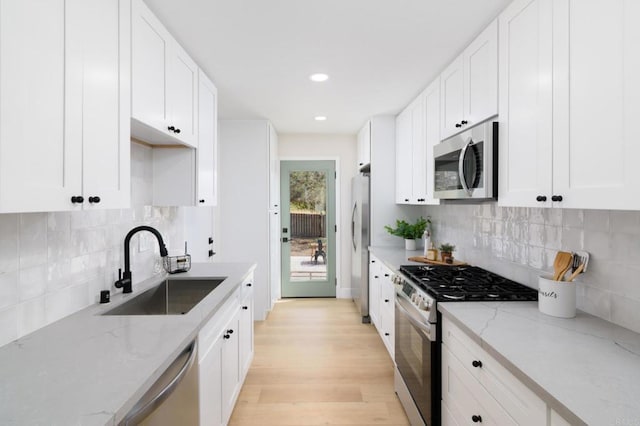 5157 Trinidad Way, San Diego, CA 92114 - kitchen featuring appliances with stainless steel finishes, a sink, white cabinets, light wood-type flooring, and recessed lighting