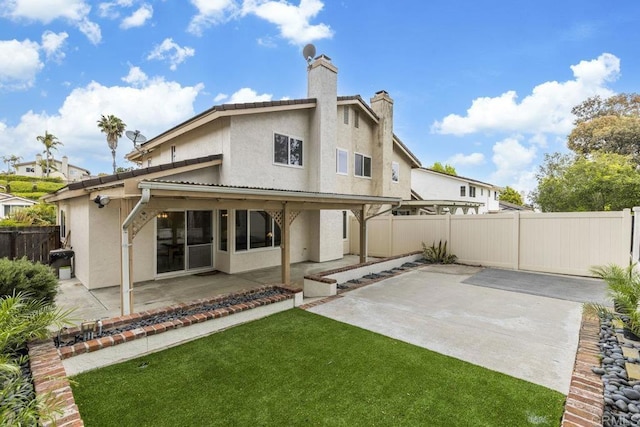 back of property with stucco siding, a patio area, and a chimney