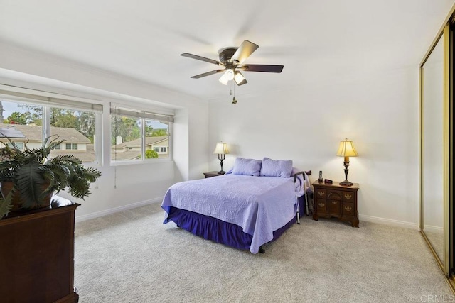 bedroom featuring light colored carpet, baseboards, and a ceiling fan