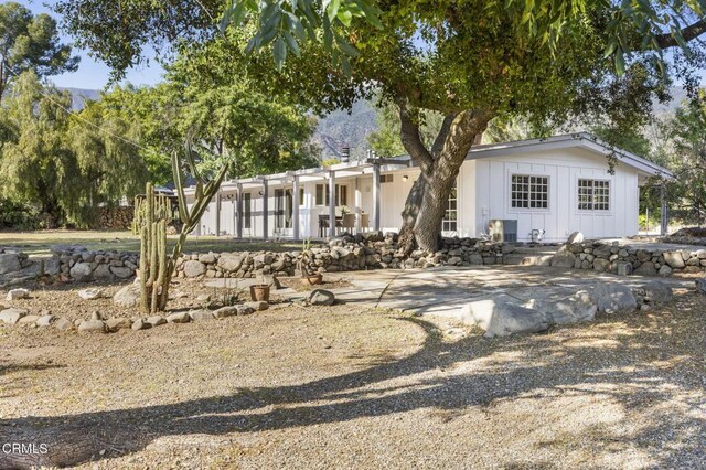 back of property featuring board and batten siding, a patio area, and a mountain view