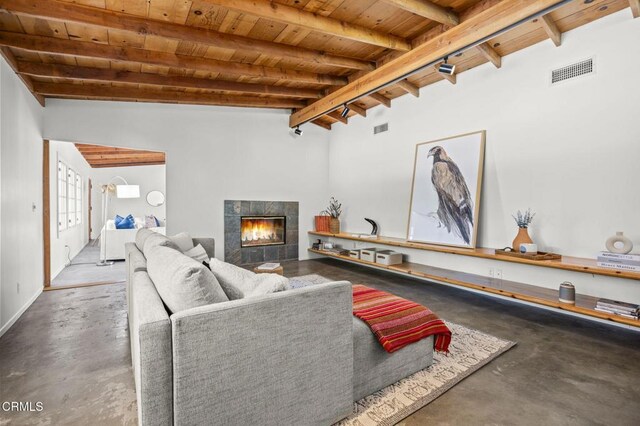 living area featuring wooden ceiling, concrete flooring, and a tile fireplace
