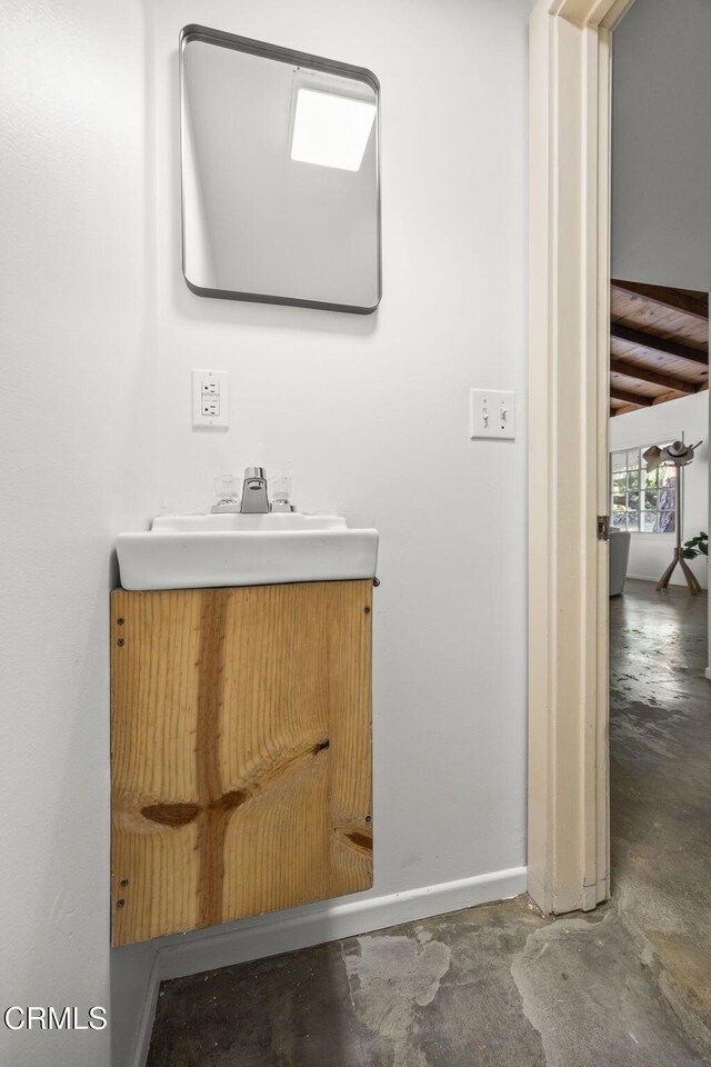 bathroom featuring unfinished concrete flooring, vanity, and baseboards