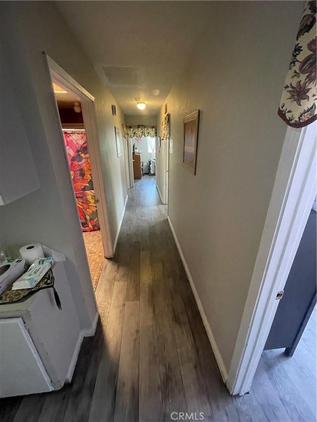 hallway featuring dark wood-style flooring and baseboards