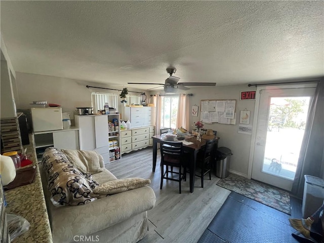 living area with a textured ceiling, light wood-style floors, and a ceiling fan