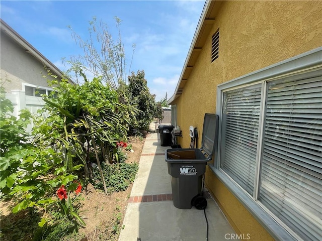 view of side of home with stucco siding and fence