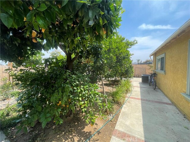 view of property exterior with fence, stucco siding, central air condition unit, and a patio