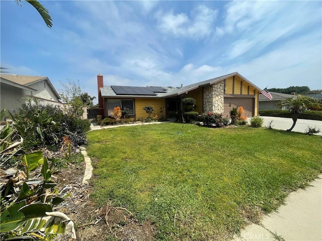 view of front of house featuring roof mounted solar panels, a garage, a chimney, driveway, and stone siding