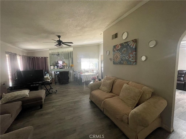 living area with a textured ceiling, ornamental molding, ceiling fan, and wood finished floors