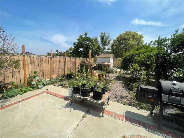 view of patio / terrace with fence, a storage shed, a grill, and an outbuilding
