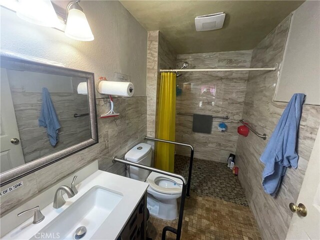 full bathroom with tile walls, tiled shower, toilet, and vanity