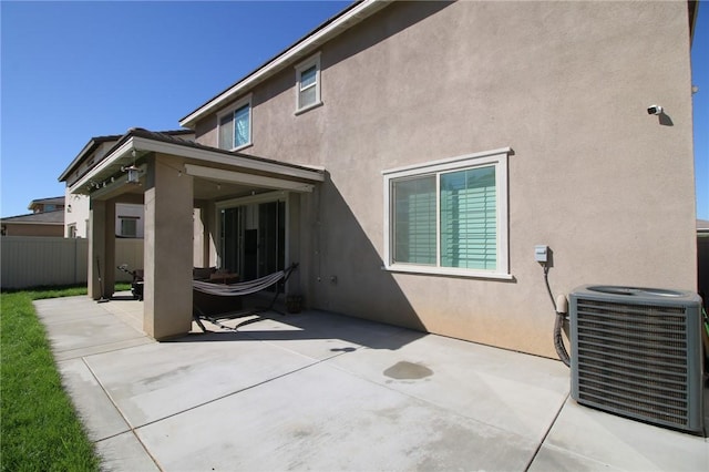 back of property with central AC unit, stucco siding, a patio area, and fence