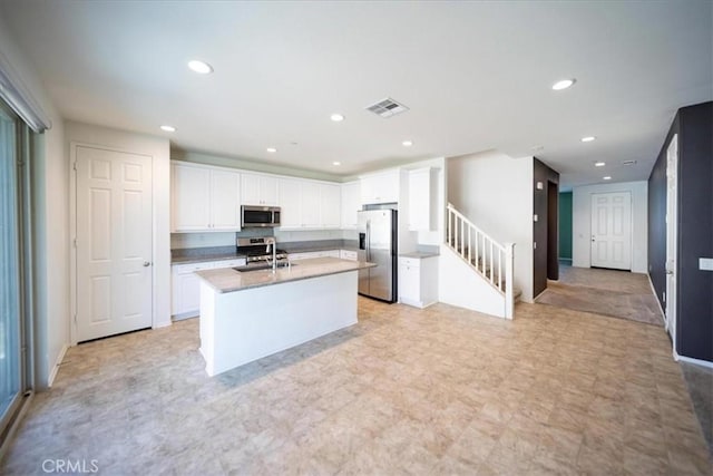 3409 Spring Wheat St, Perris, CA 92570 - kitchen with stainless steel appliances, white cabinets, an island with sink, a sink, and recessed lighting
