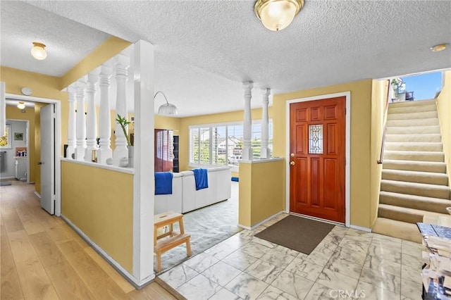 5134 Veronica St, Los Angeles, CA 90008 - entryway featuring baseboards, light marble finish flooring, stairway, ornate columns, and a textured ceiling