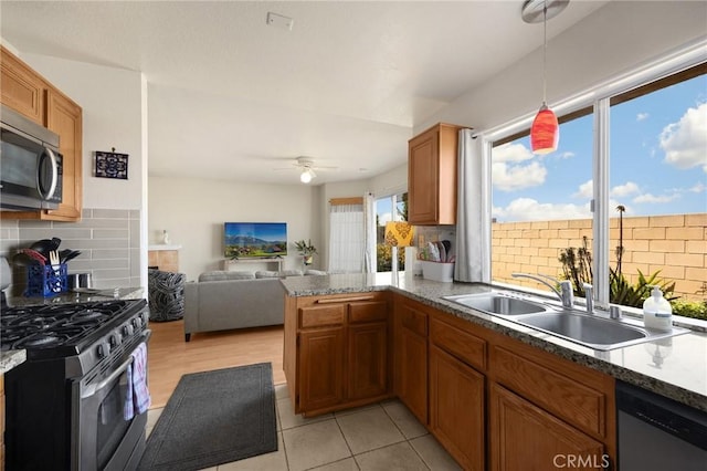 27559 Avenida Interno, Menifee, CA 92585 - kitchen with stainless steel appliances, a sink, backsplash, brown cabinetry, and open floor plan