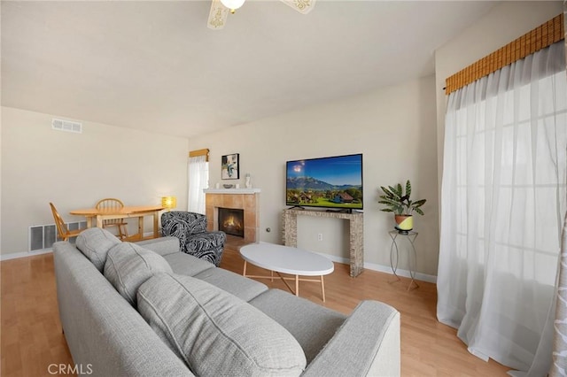 27559 Avenida Interno, Menifee, CA 92585 - living room featuring light wood-style floors, a tiled fireplace, healthy amount of natural light, and baseboards