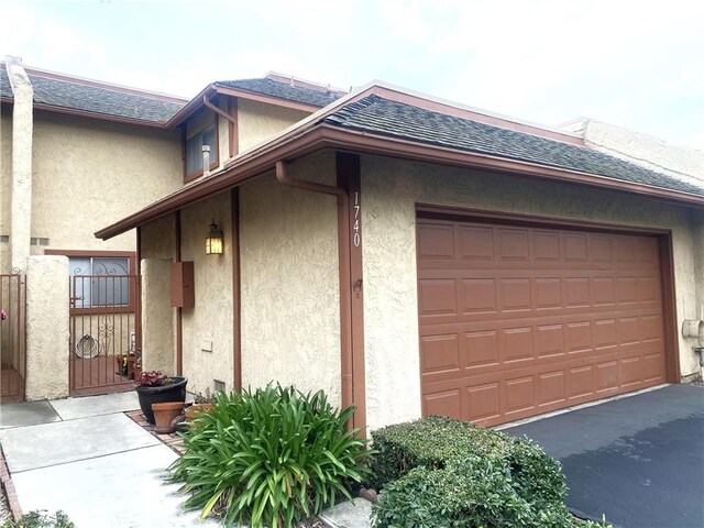 1740 Silver Maple Dr, La Habra, CA 90631 - view of home's exterior with stucco siding, a garage, a shingled roof, and asphalt driveway