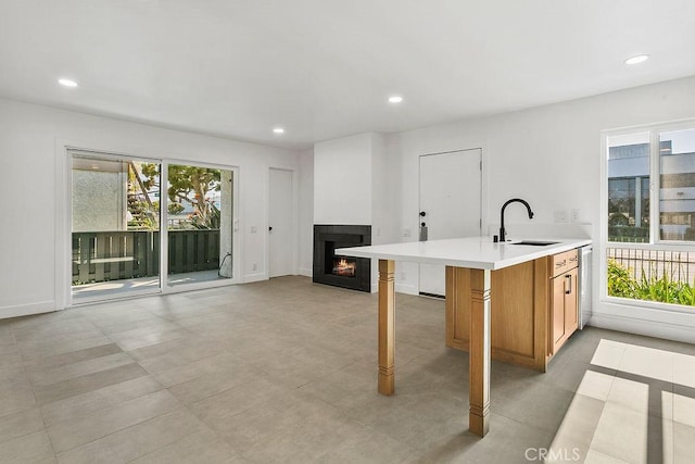 2835 S Fairview St Unit C, Santa Ana, CA 92704 - kitchen with a sink, light countertops, a multi sided fireplace, brown cabinetry, and dishwasher