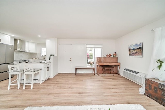 3004 Via Buena Vis Unit C, Laguna Woods, CA 92637 - kitchen with wall chimney exhaust hood, freestanding refrigerator, a wall unit AC, light wood finished floors, and white cabinetry