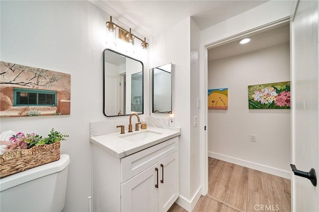 3004 Via Buena Vis Unit C, Laguna Woods, CA 92637 - bathroom featuring wood finished floors, toilet, vanity, and baseboards