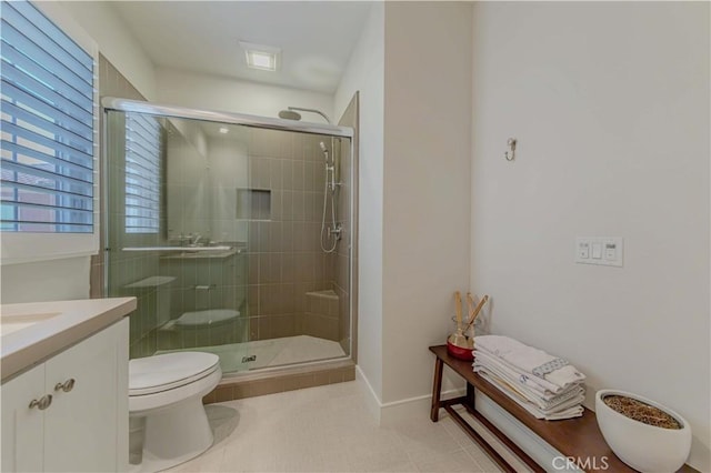 bathroom with a shower stall, toilet, vanity, and baseboards