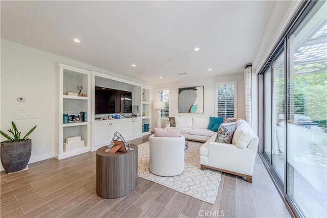 living room featuring light wood finished floors, recessed lighting, and baseboards