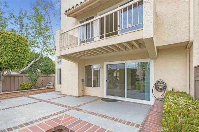 611 Colonial Cir, Fullerton, CA 92835 - view of exterior entry featuring stucco siding, fence, a patio, and a balcony