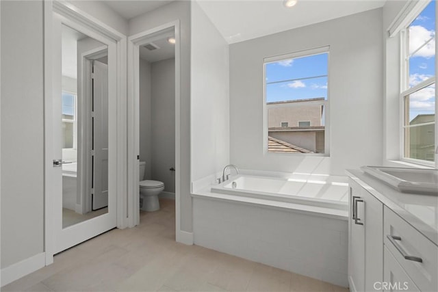 full bath with toilet, a garden tub, healthy amount of natural light, and vanity