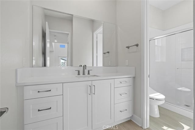 bathroom featuring toilet, a shower stall, vanity, and wood finished floors