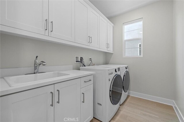 laundry room featuring cabinet space, washing machine and clothes dryer, baseboards, and light wood-style flooring